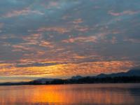 Die Unterseite der Wolken über dem Chiemsee leuchten vor dem Sonnenaufgang